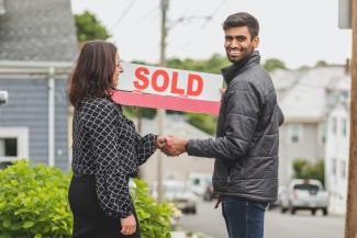 Image of two people holding up a "sold" sign